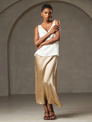 Woman in white 19Momme silk sleeveless V-neck tank top with V-back, paired with a gold silk skirt.