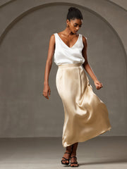Woman wearing a white mulberry silk sleeveless V-neck tank top and a champagne silk midi skirt.