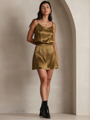 Woman wearing a gold mulberry silk spaghetti strap camisole and matching silk skirt.