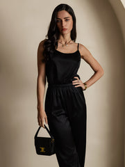 Woman wearing a black 19 Momme mulberry silk spaghetti strap camisole and matching silk pants.