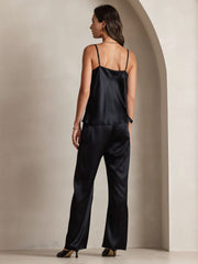 Woman in a black 19 Momme mulberry silk spaghetti strap cowl neck camisole top and matching silk pants.
