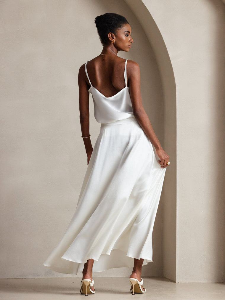 Woman in a white 19 Momme mulberry silk spaghetti strap cowl neck camisole top and matching skirt.