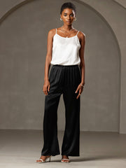 Woman in a white 19 Momme mulberry silk spaghetti strap camisole and black silk wide-leg pants.