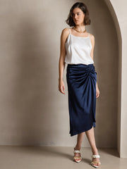 Woman wearing a white 19Momme mulberry silk spaghetti strap camisole and a navy ruched silk skirt.
