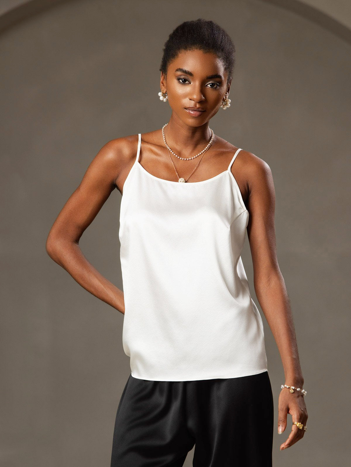 White mulberry silk spaghetti strap camisole with round neck, worn by a woman.